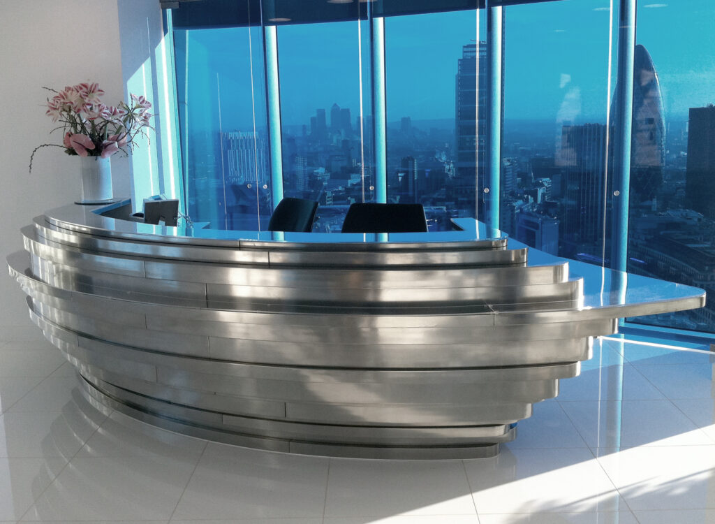 Metalier liquid metal polished gunmetal reception desk with a unique tiered architectural design in a high-rise office – England.
