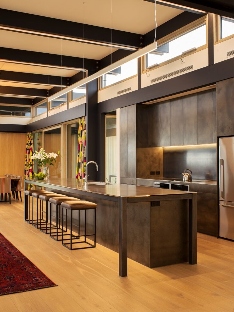 Metalier liquid metal smoky bronze finish on a large central kitchen island and matching wall cabinetry in a luxury open-plan home – England.