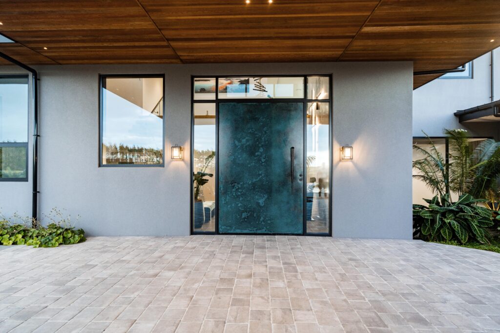 Modern contemporary home entrance with oversized teal pivot door, wood soffit ceiling, and minimalist exterior lighting – Australia