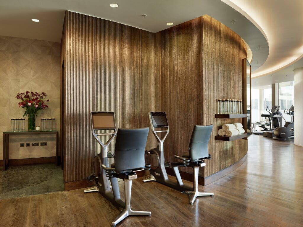 Modern luxury gym and wellness center featuring curved interior walls clad in vertical fluted bronze Metalier liquid metal panels — Australia.