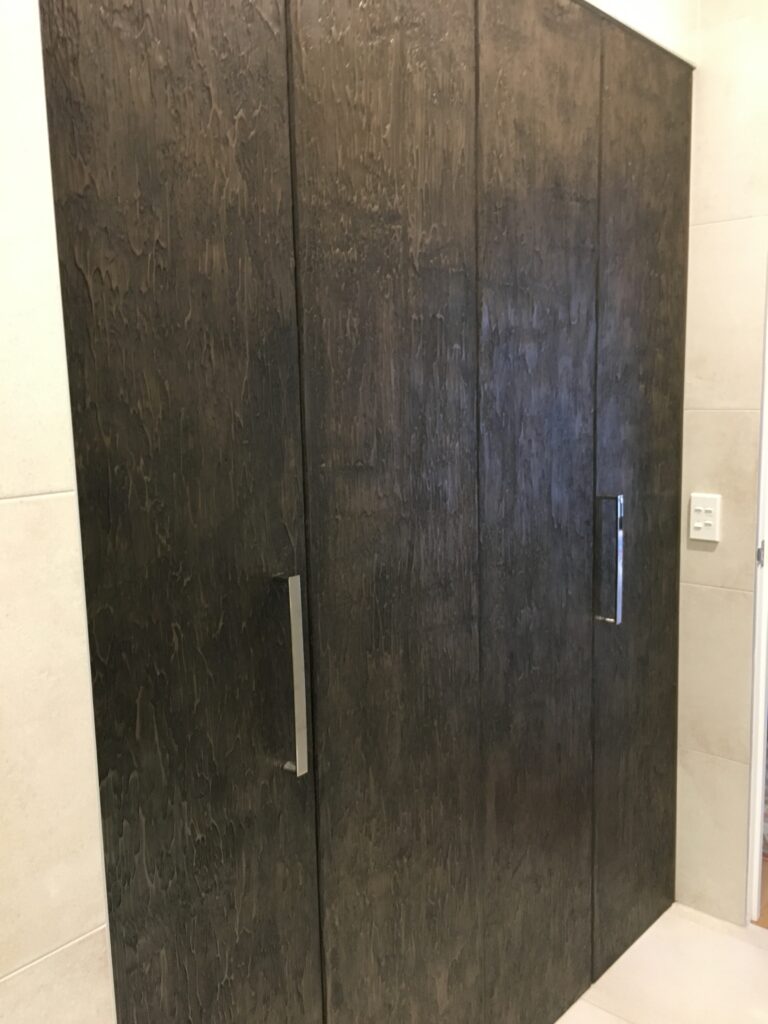 Tall double doors in smoky bronze papyrus finish with textured dark patina and sleek vertical metal handles, contemporary interior - India