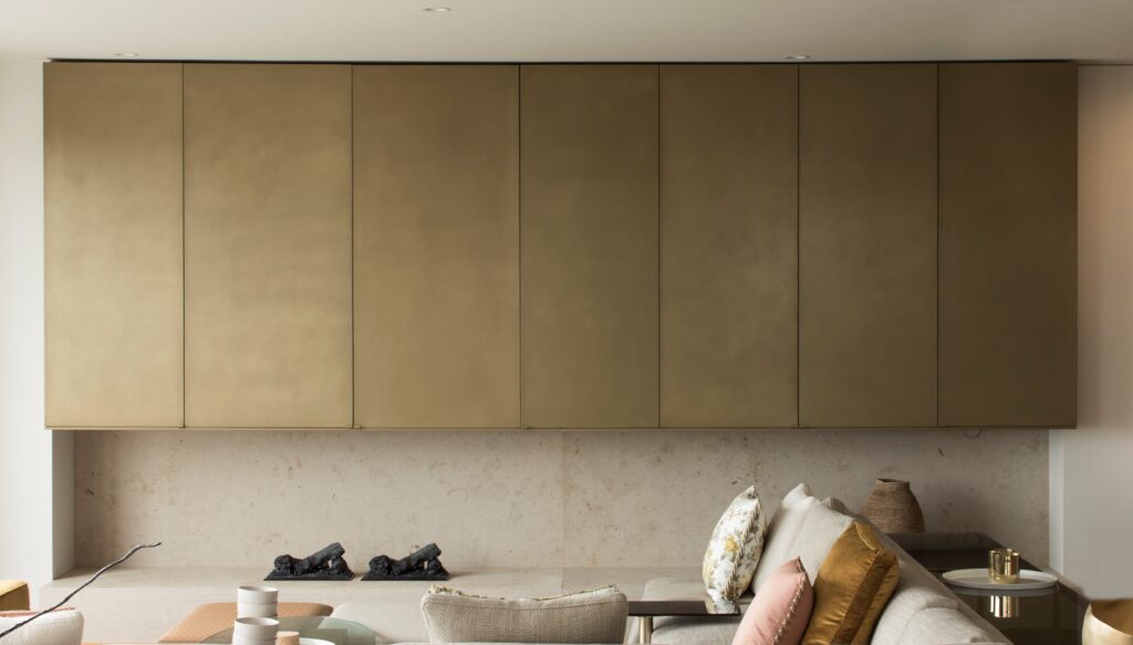 “Minimalist interior featuring wall of seamless brass cabinetry with soft patina finish above stone bench seating, contemporary luxury design - Auckland, New Zealand