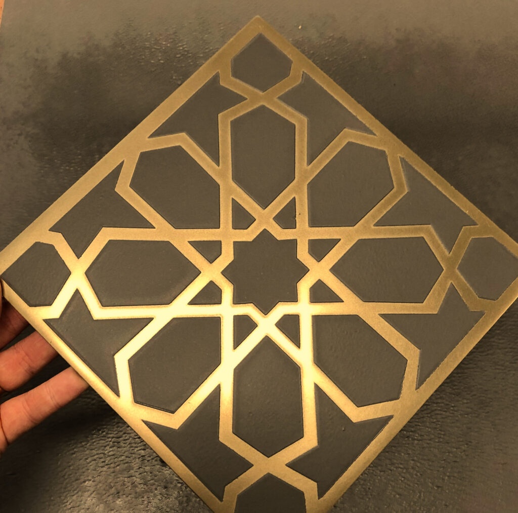 Gold Islamic geometric art in a Metalier decorative finish on a dark grey Metalier test spray panel